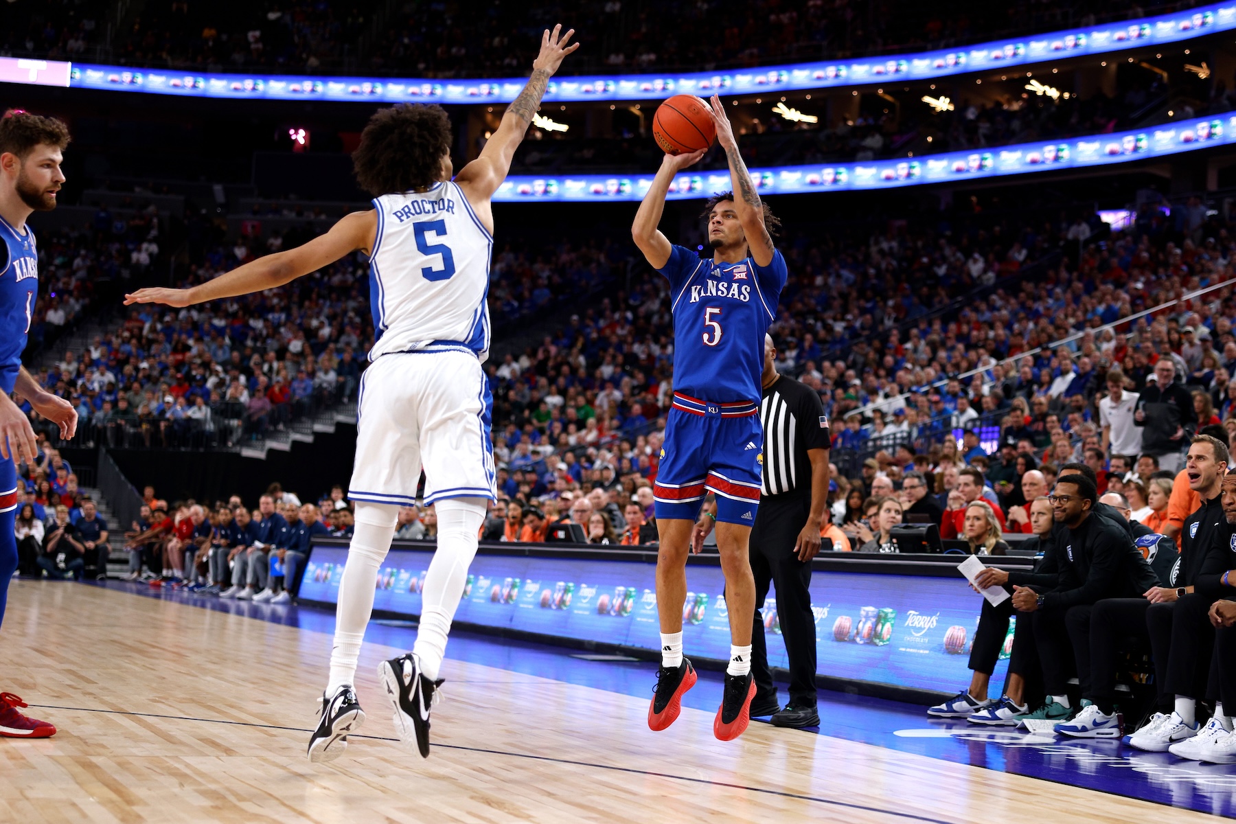 Zeke Mayo #5 of the Kansas Jayhawks puts up a three-point shot against Tyrese Proctor