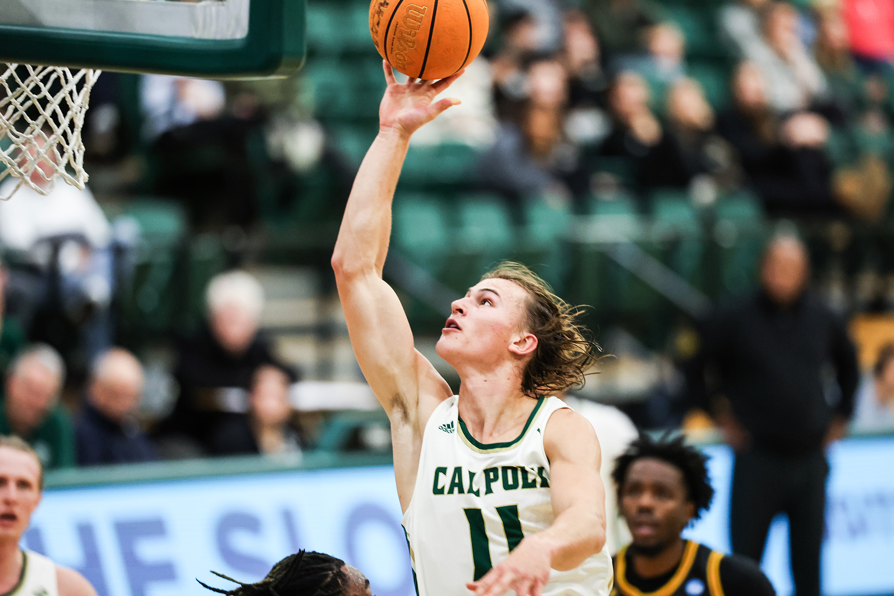 Cal Poly guard Owen Koonce soars through the air with the ball in his right hand about to attempt a shot.