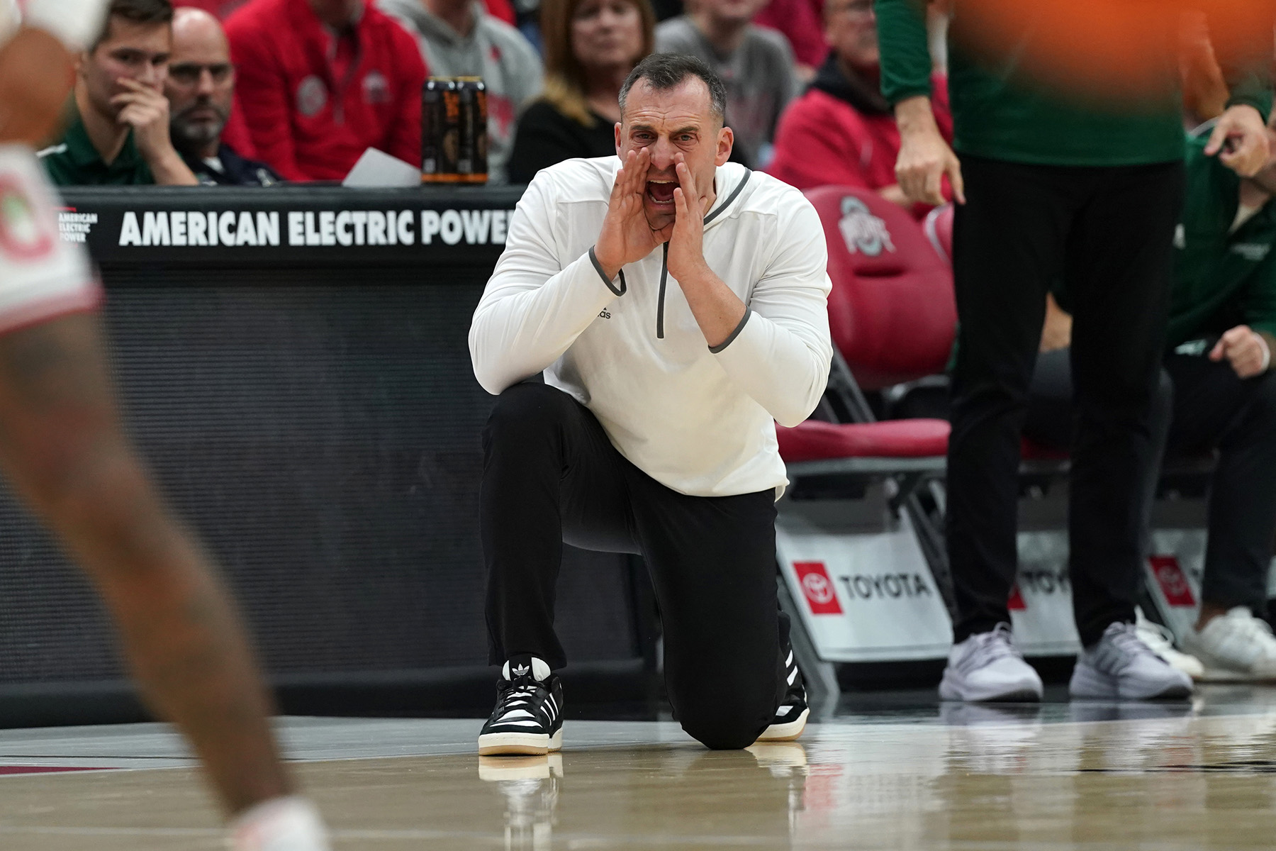 Green Bay coach Doug Gottlieb on a knee screaming out instructions to his team from the sideline.