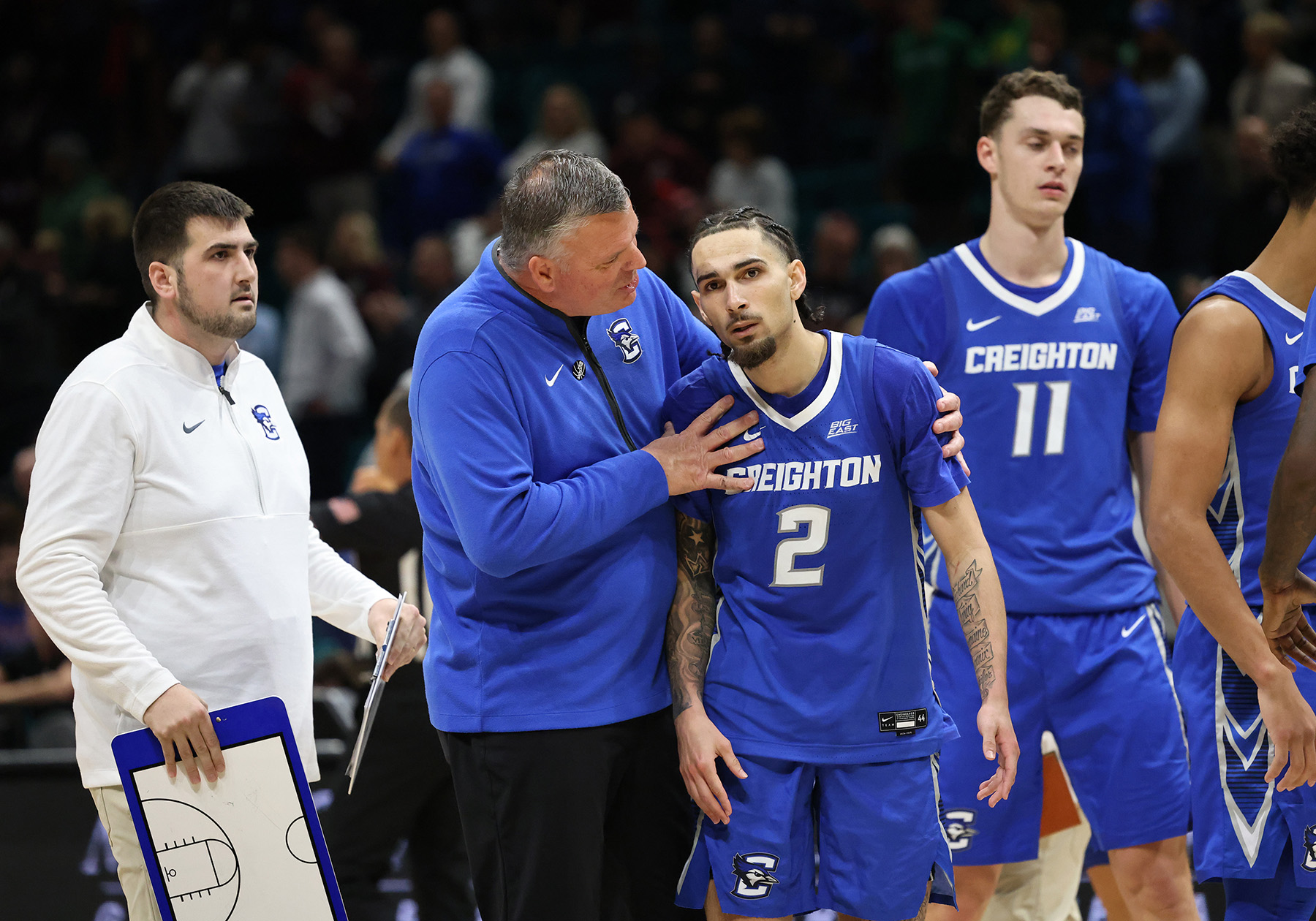 Creighton head coach Greg McDermott with his arms around guard Pop Isaacs during a game.