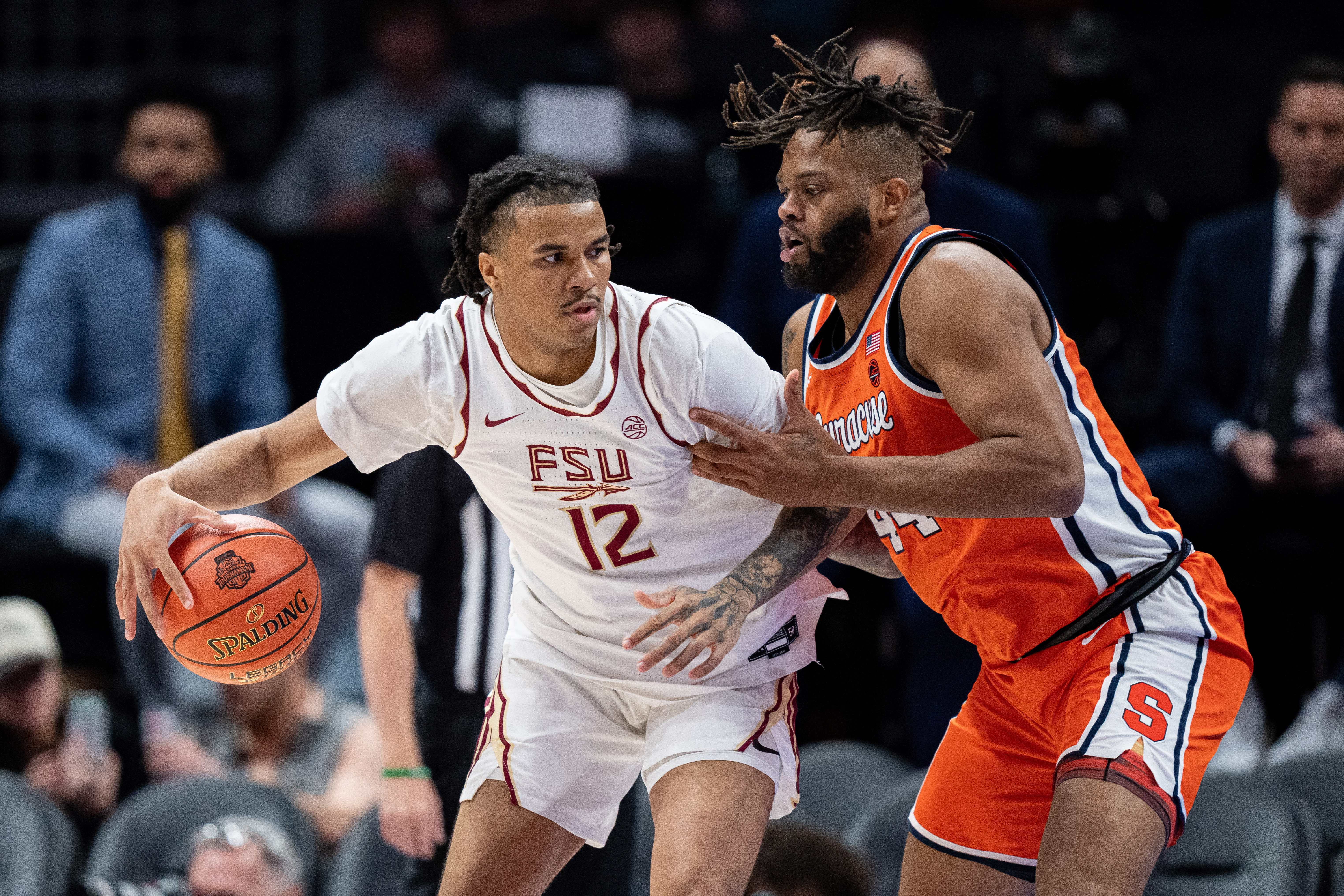 Basketball player Malique Ewin of the Florida State Seminoles is guarded by Eddie Lampkin Jr. of the Syracuse Orange in the first half during the first round of the ACC men's basketball tournament at Spectrum Center on March 11, 2025