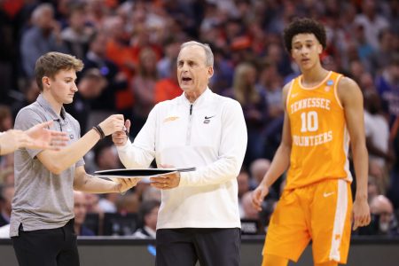 Rick Barnes takes a pen and clip board from a staffer