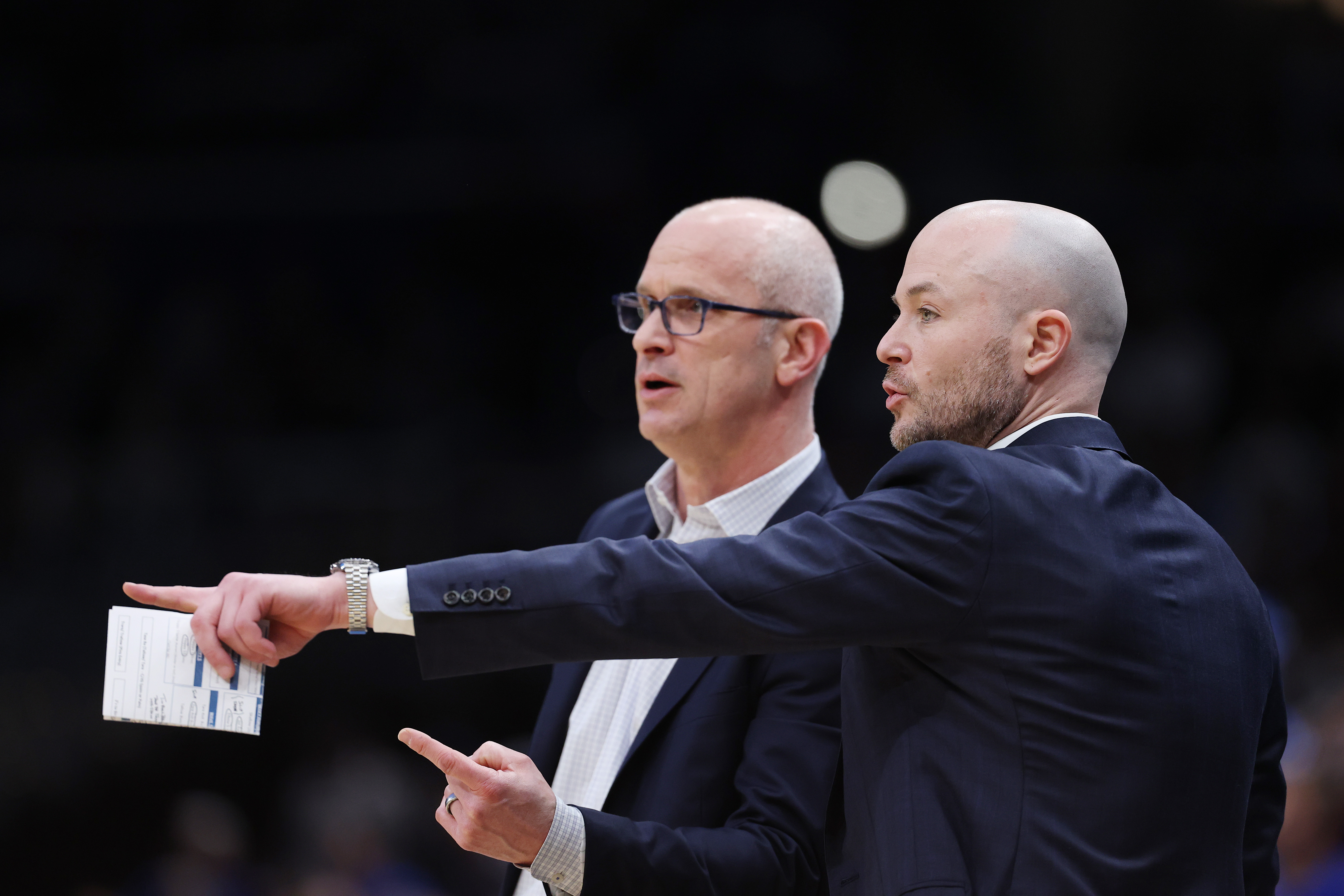Assistant coach Luke Murray talks with head coach Dan Hurley of the UConn Huskies during the first half of a game against the Duke Blue Devils in the 2026 NCAA Elite Eight.