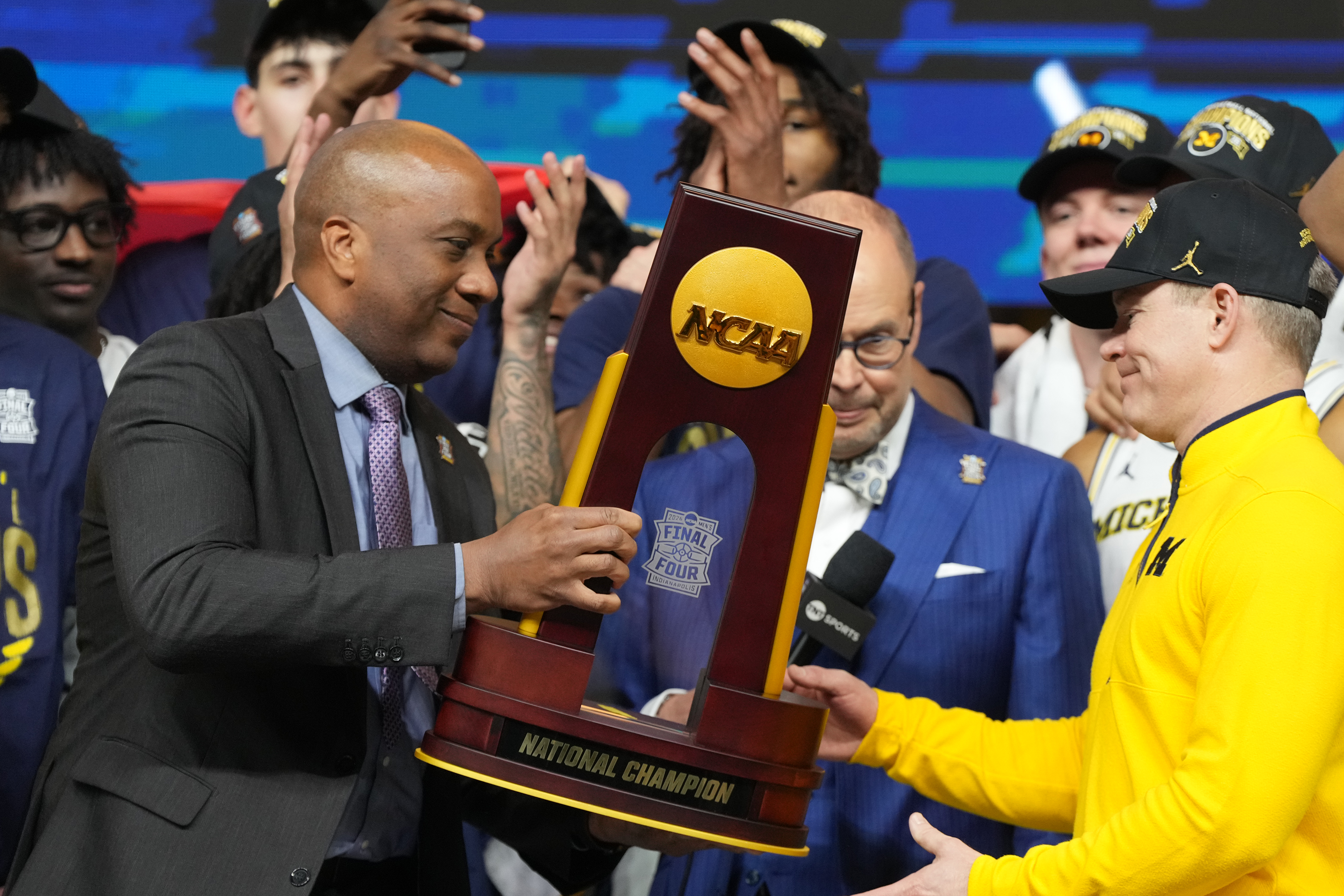 Men’s selection committee chair Keith Gill hands the NABC National Championship trophy to Michigan coach Dusty May