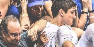 Image of Brett Friedlander posing with "Cameron Crazies" as he holds a carboard sign that reads: "Do Not Enter. New Laptop."