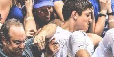 Image of Brett Friedlander posing with "Cameron Crazies" as he holds a carboard sign that reads: "Do Not Enter. New Laptop."