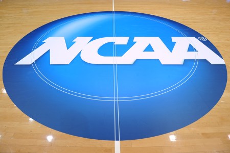 Picture of the NCAA logo painted at center court of a basketball arena
