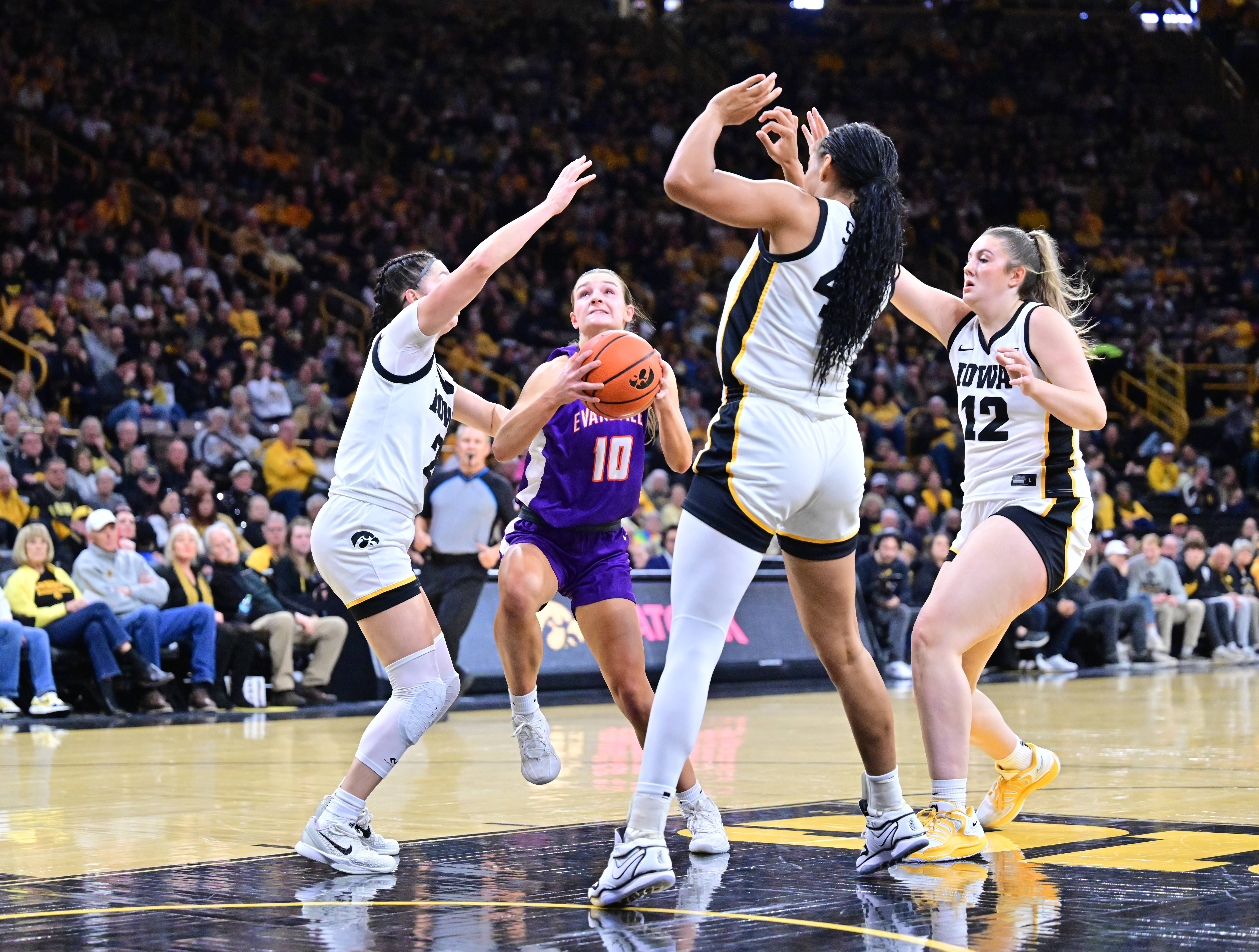 Evansville guard Camryn Runner drives the lane with three Iowa defenders closing in on her