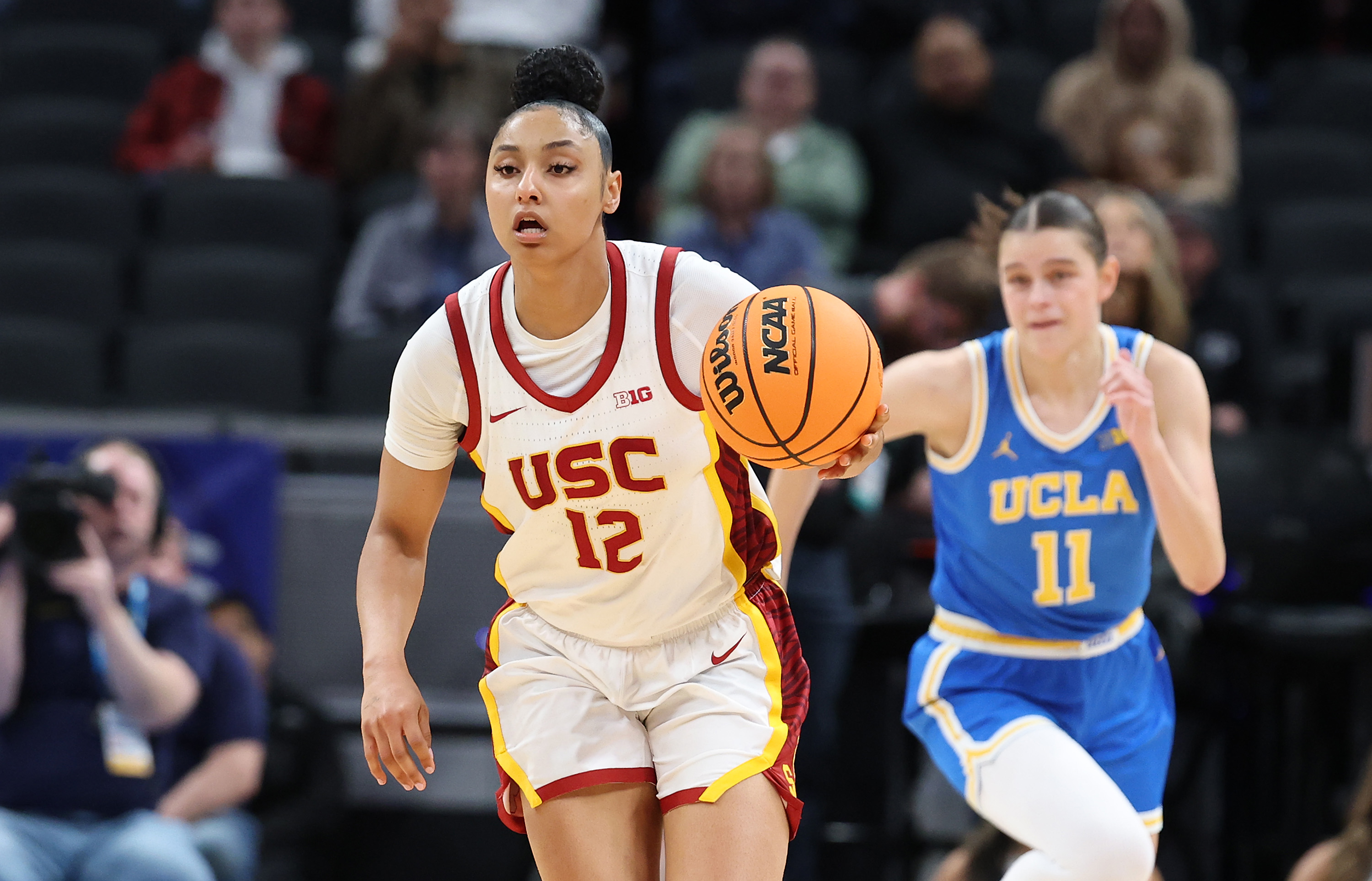 USC guard JuJu Watkins dribbles the ball with a UCLA defender in the background