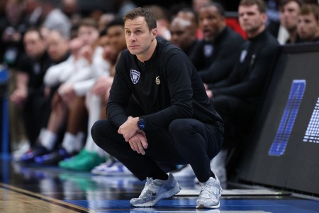 Jon Scheyer squats on the Duke sidelines as he watches his team in action