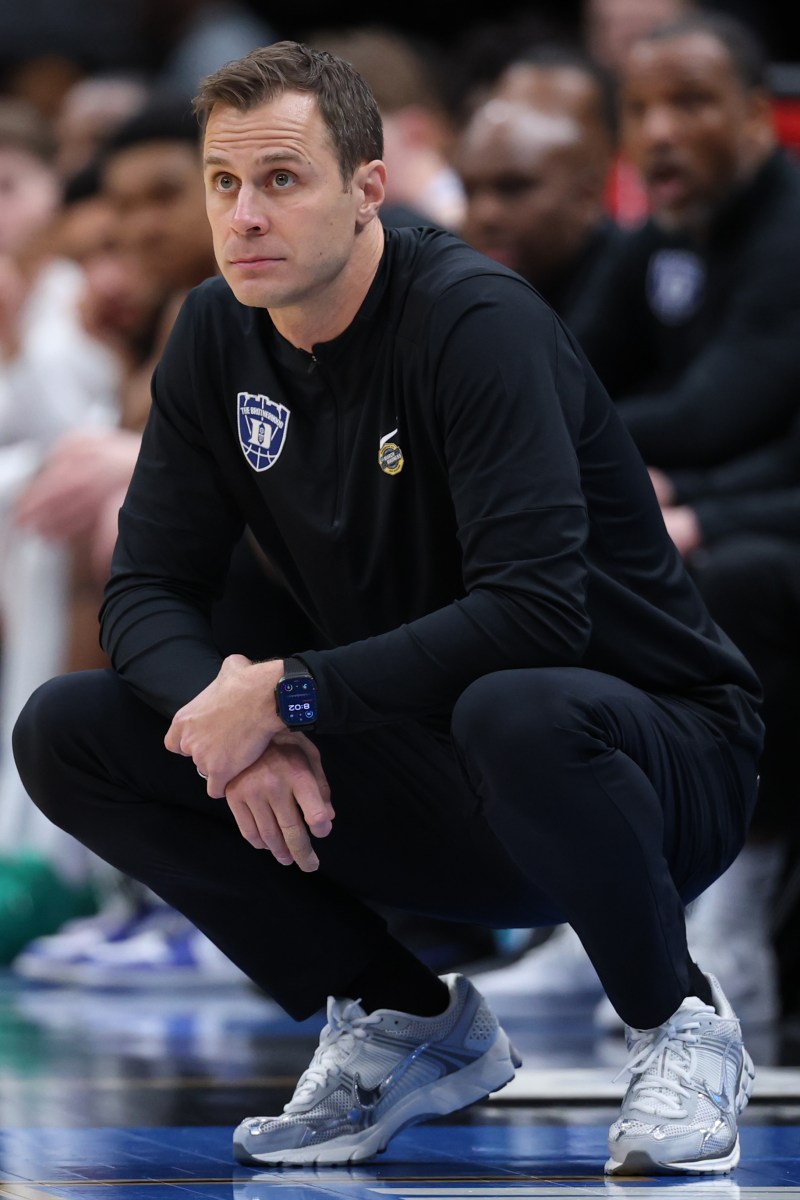 Jon Scheyer squats on the Duke sidelines as he watches his team in action